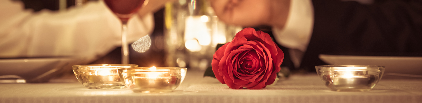 Romantischer Esstisch mit 2 Gläsern Wein und Kerzen