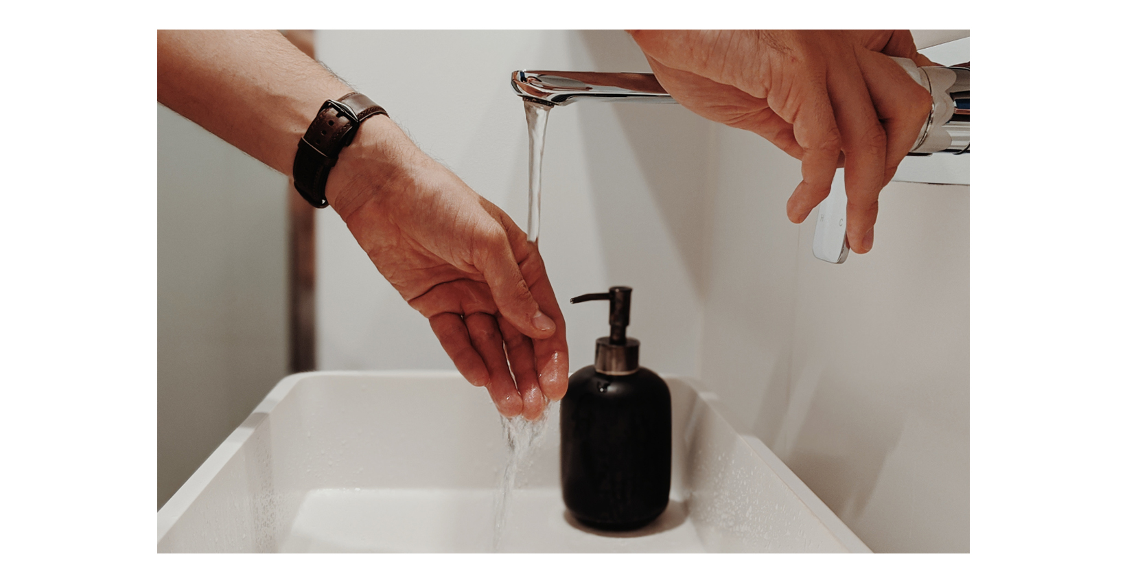 Ein Mann wäscht sich die Hände in einem Waschbecken im Badezimmer
